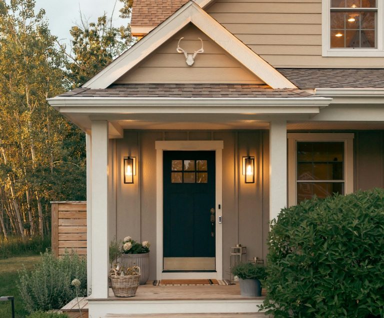 Bien chez soi by Polymathia Group Porte d'entrée bleue avec lanternes, maison en bois beige et jardin verdoyant.
