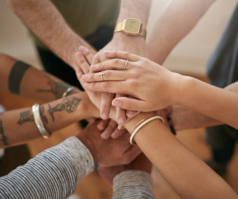 Main tenant des mains empilées les unes sur les autres, symbolisant l'unité et la collaboration.