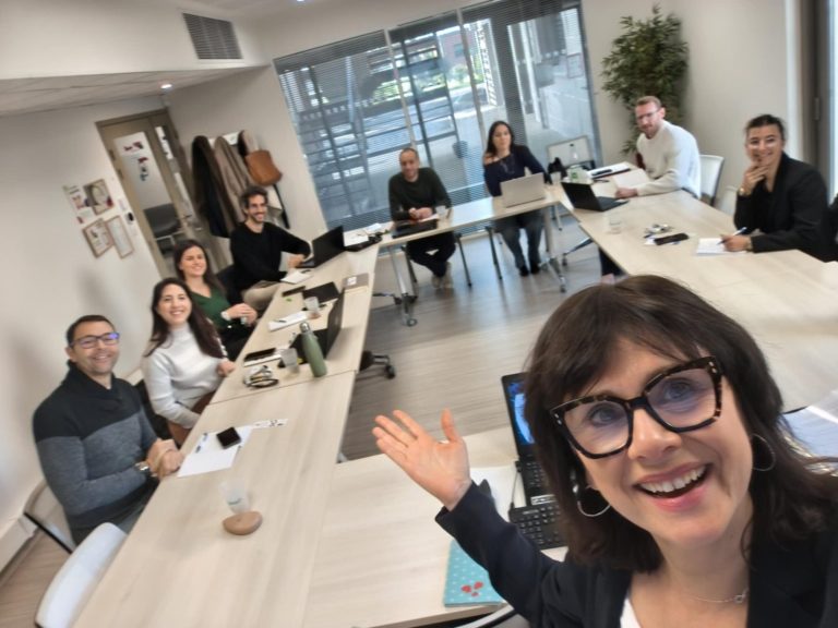 Groupe de personnes en réunion formation dans une salle en U, moderne, souriants et accueillants.