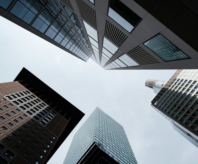 Service aux Entreprises by Polymathia Group Vue en contre-plongée des façades de gratte-ciels sous un ciel nuageux.