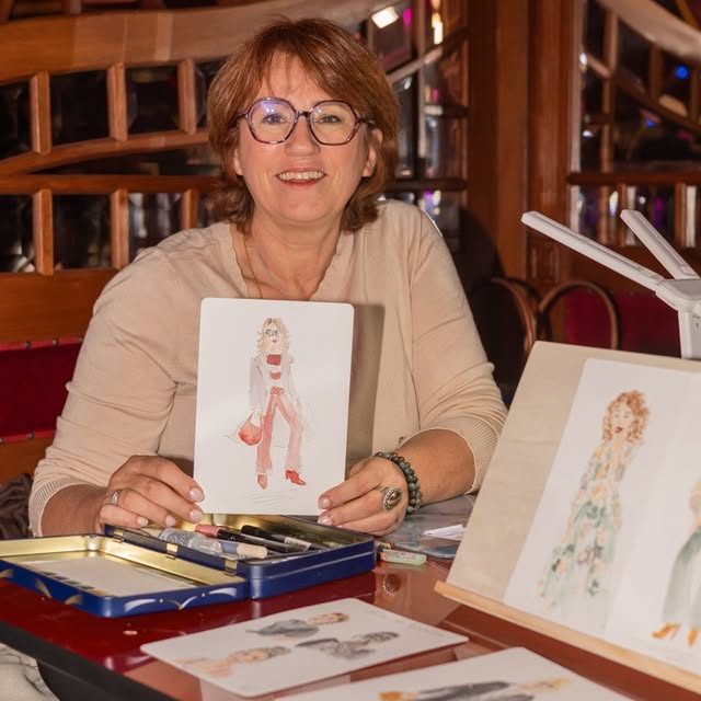 Femme souriante portant des lunettes, vêtue d'un haut noir, avec un fond artistique.