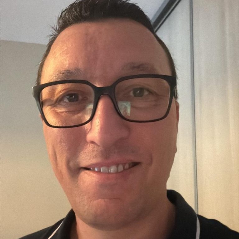 Femme souriante portant des lunettes, vêtue d'un haut noir, avec un fond artistique.