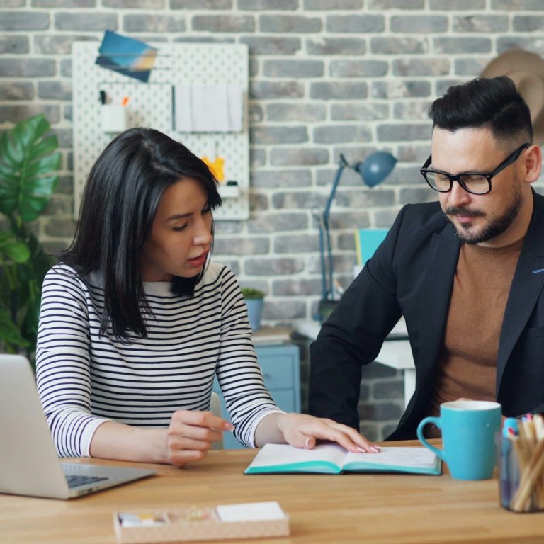 Associés et partenaire supplémentaire PREMIUM Une femme et un homme regardent un livre dans un bureau