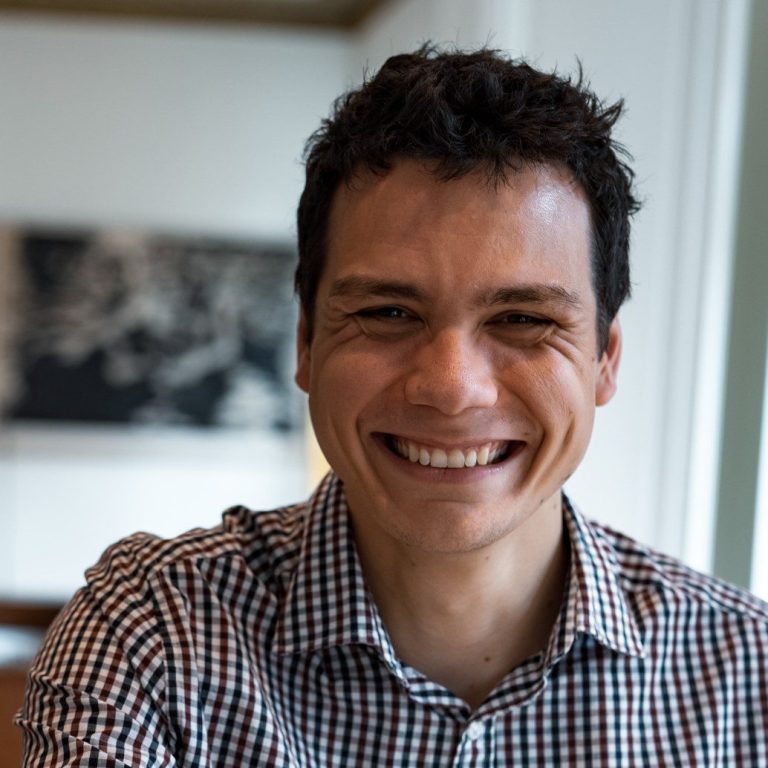 Femme souriante portant des lunettes, vêtue d'un haut noir, avec un fond artistique.