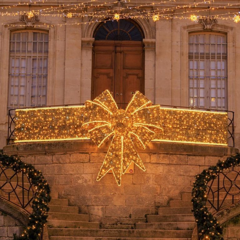 Bannière lumineuse en forme de nœud à l'entrée d'un bâtiment, décorée pour Noël.