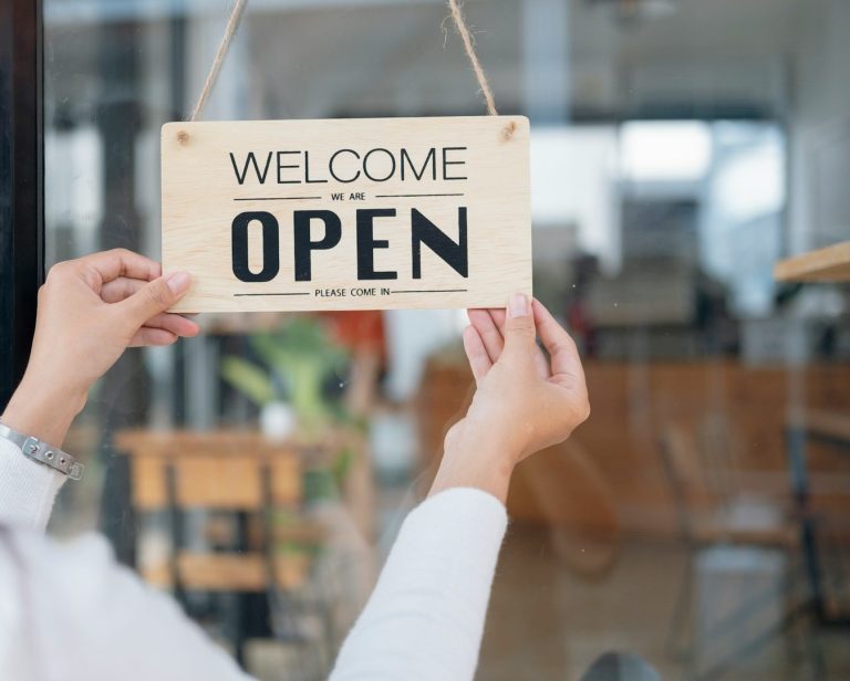 Panneau "Bienvenue, Ouvert" accroché à la porte d'une boutique.