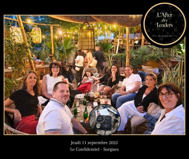 Groupe de personnes assises en extérieur, buvant un verre entourées de plantes et de lumières.