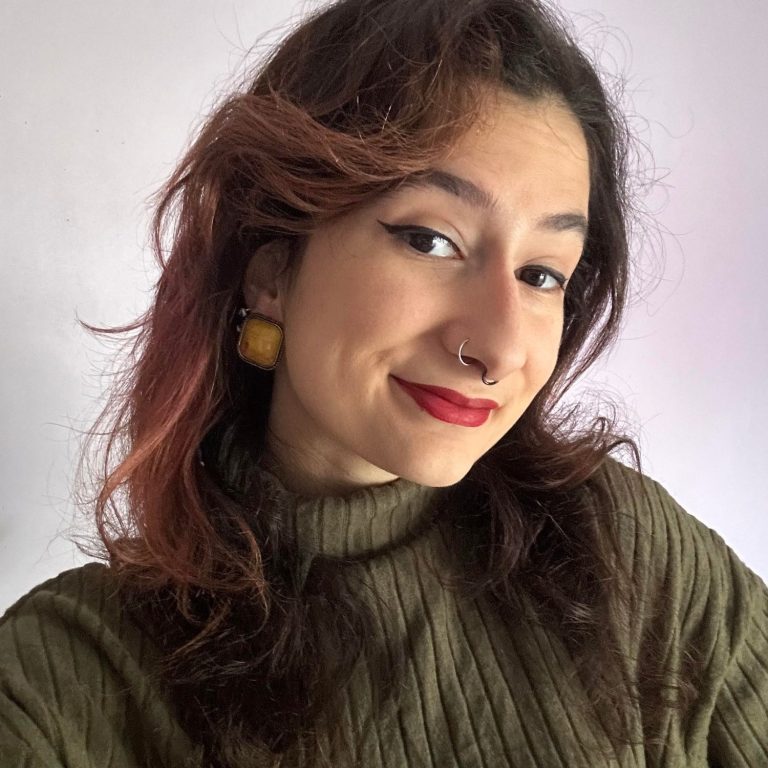 Femme souriante portant des lunettes, vêtue d'un haut noir, avec un fond artistique.