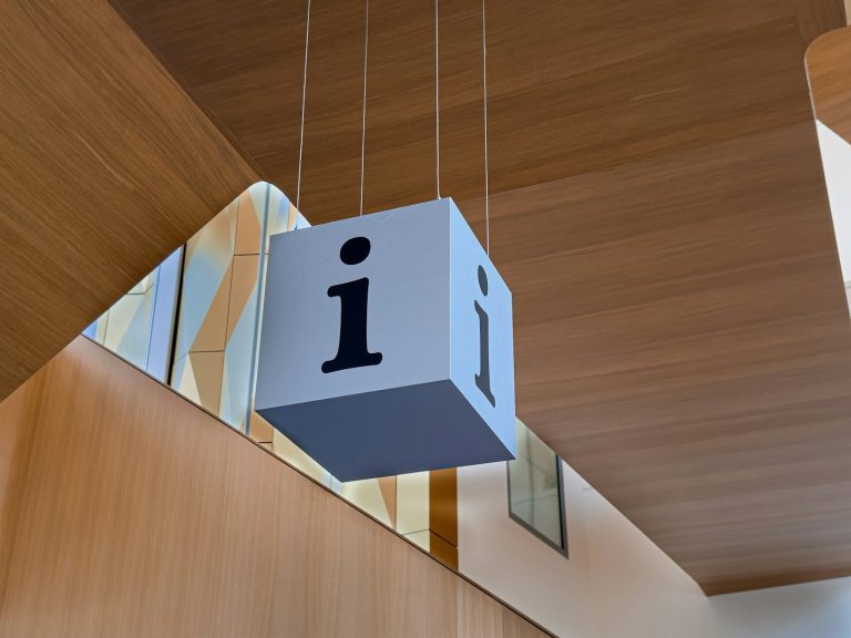 Cube suspendu avec un "i" en noir, accroché au plafond en bois.