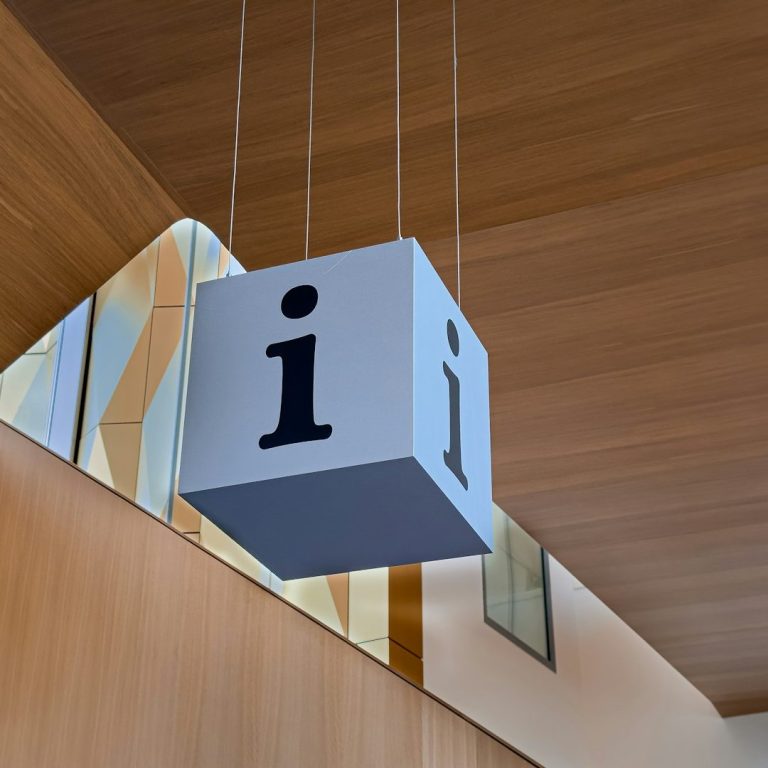 Cube suspendu avec la lettre "i" en noir sur un fond clair et en bois.