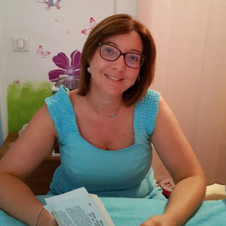 Femme souriante portant des lunettes, vêtue d'un haut noir, avec un fond artistique.