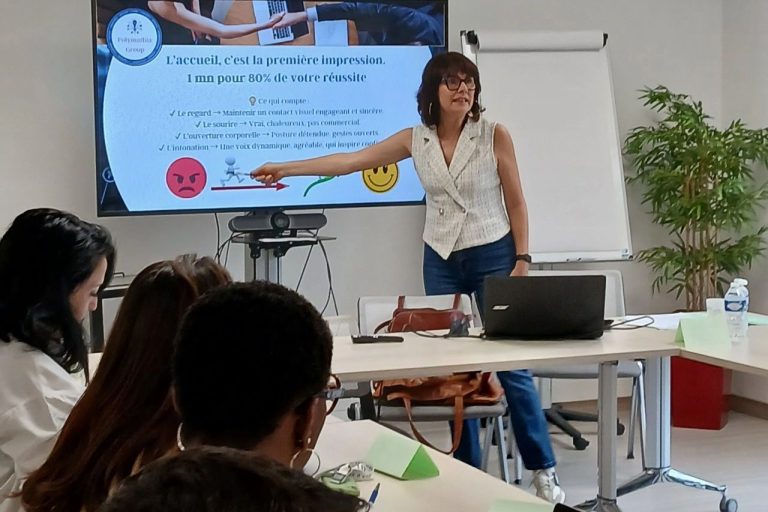 Femme travaillant sur un ordinateur portable, avec un carnet et des stylos sur son bureau.