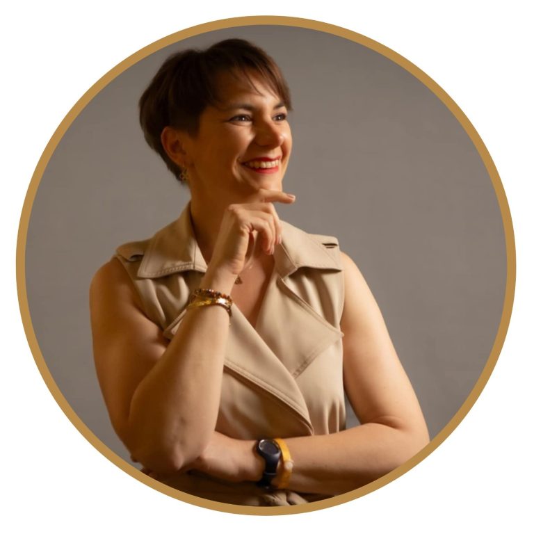 Femme souriante avec un haut beige, posant avec un bras croisé. Ludivine Antoine